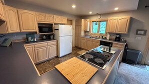 Une cuisine moderne avec des meubles en bois, un four à micro-ondes encastré, un réfrigérateur, une cuisinière et un évier.