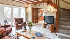 Una sala de estar acogedora con una escalera de madera, un comedor y una cocina al fondo.