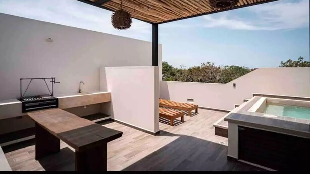 Eine Dachterrasse mit Pool, Holzmöbeln und einer hängenden Leuchte.