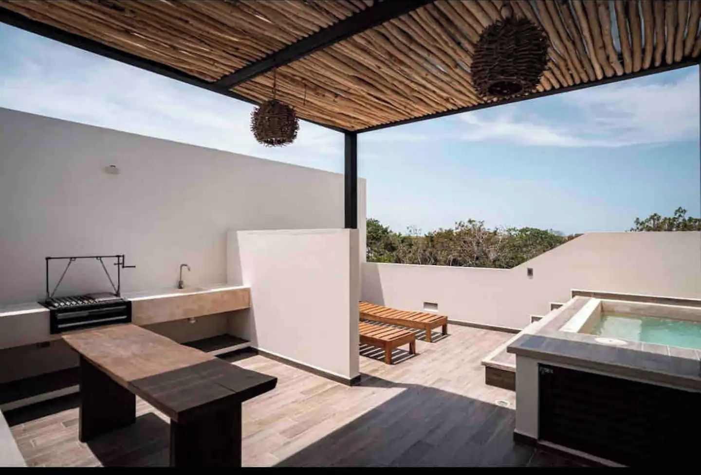 A rooftop terrace with a pool, wooden furniture, and a hanging light fixture.