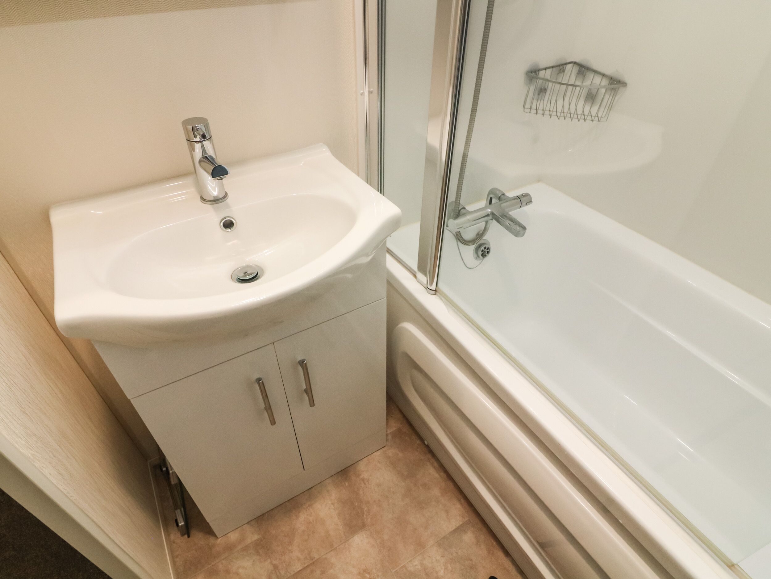 A bathroom with a white sink, a mirror, a shower, and a toilet.