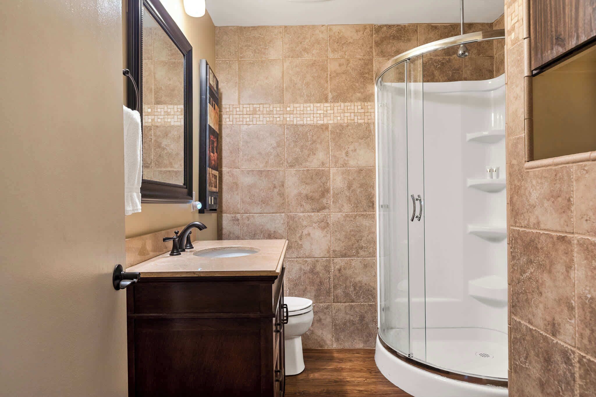 A bathroom with a sink, toilet, and a glass-enclosed shower.