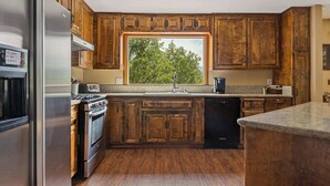 A kitchen with wooden cabinets, a stainless steel refrigerator, a stove, and a dishwasher. - Our Secret Getaway An Adventurer's Oasis (Lake Arrowhead)