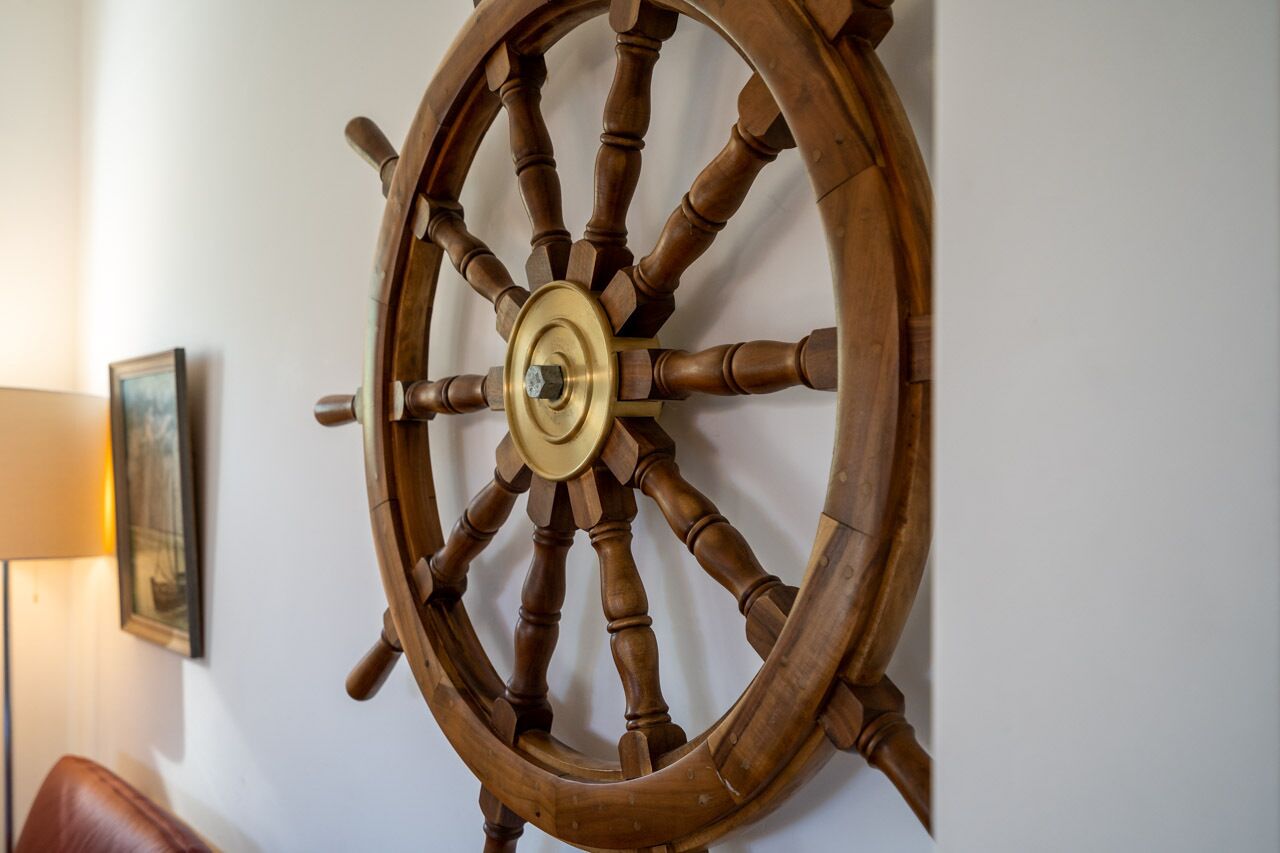 Un gouvernail de bateau en bois fixé au mur.