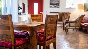 Un comedor con mesas y sillas de madera, una puerta roja y obras de arte en las paredes.