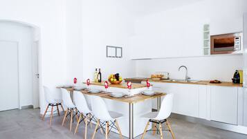 A modern kitchen with white cabinetry, a wooden dining table, and white chairs.