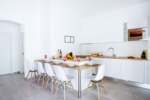 Una cocina moderna con armarios blancos, una mesa de comedor de madera y sillas blancas.