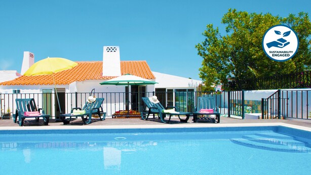 Un espace piscine avec des chaises longues et un coin salon abrité.