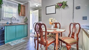 A kitchen with teal cabinets, a wooden dining table with chairs, and a hanging plant. - Bring Your Pets! Midway Abode w/ Yard & Fire Pit (Midway)