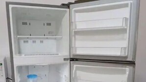 An open refrigerator with multiple shelves and compartments. - G Apartments (Willemstad)