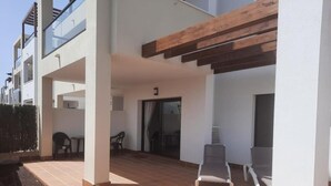 Un espace extérieur abrité, doté d’un sol carrelé, de deux chaises et d’une table.