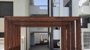 Une structure architecturale moderne avec une ossature en bois, un sol carrelé et un ciel dégagé.