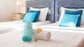 Un lit bien fait, avec deux oreillers, une serviette enroulée et des coquillages.