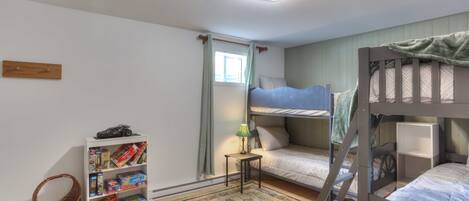 A child's room with bunk beds, a bookshelf, a small table with a lamp, and a patterned rug.