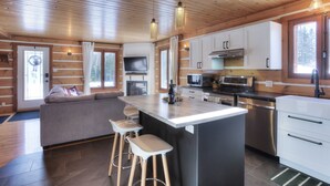 A modern kitchen with wooden walls, a central island, bar stools, and a built-in TV.