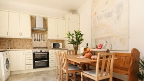 Una cocina con armarios blancos, microondas, estufa y una mesa de comedor con sillas.