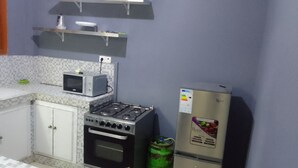 Una cocina compacta con microondas, estufa, horno y refrigerador.