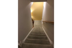 Stairs lead to an upper floor with a carpeted handrail and a plain white wall.