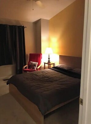 Cozy retreat with a single bed, a comfortable chair, and a convenient table with a lamp.