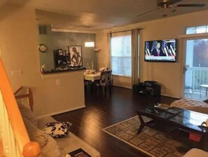 Relax in this spacious living room with a high ceiling, ceiling fan, and large window offering a view.