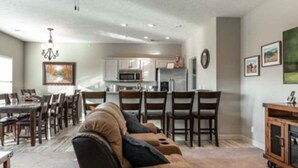 Ein modernes Wohnzimmer mit Sofa, Essbereich, Küche und Deckenventilator.