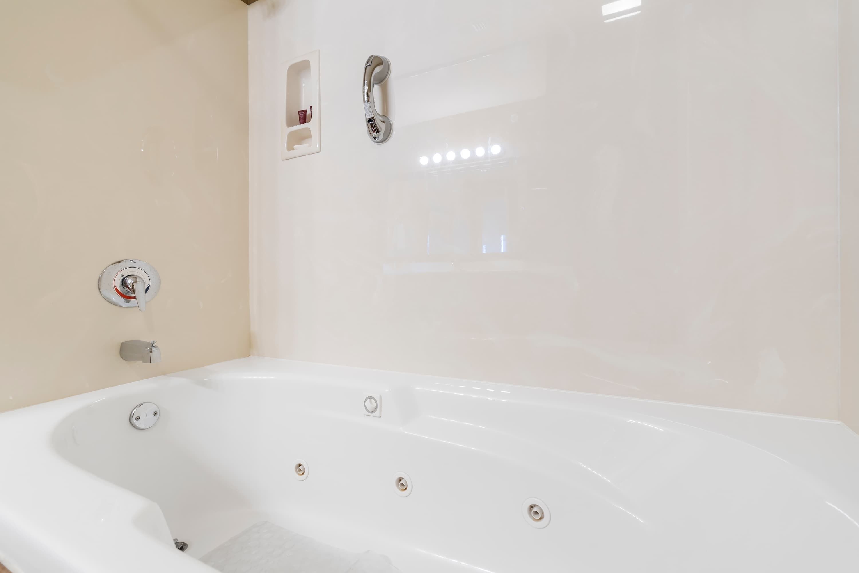 Eine weiße Badewanne mit Chromarmatur und Bedienfeld.
