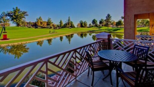 Un espace patio offrant une vue sur un terrain de golf et un étang.