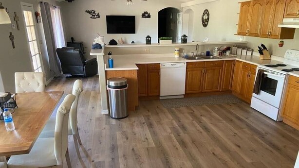 A kitchen with wooden cabinets, a dishwasher, a stove, and a dining area with a table and chairs.