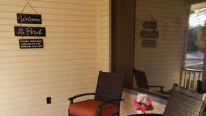 A porch with two chairs and a table, a 'Welcome to our Porch' sign, and a view of the outdoors.