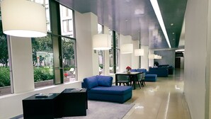 Un hall d'entrée moderne avec des sièges bleus, de grandes fenêtres et un sol propre et bien entretenu.