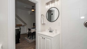 Un baño con un lavamanos blanco, un espejo redondo y una toalla colgada en la pared.