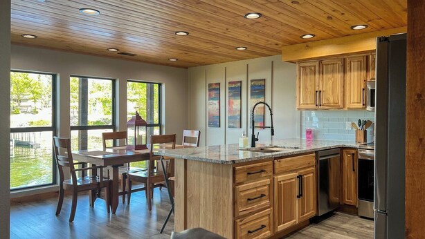 Una cocina moderna con armarios de madera, encimera de granito y un área de comedor con sillas.