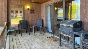 Una terraza de madera con una parrilla, sillas y un letrero de bienvenida.
