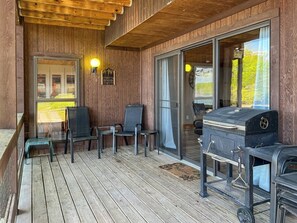 A wooden deck with a grill, chairs, and a welcome sign.