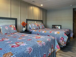 A bedroom with two beds, a nightstand with a vase of flowers, and a wooden headboard.