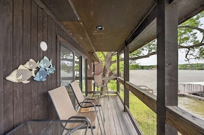 A wooden deck with chairs and a table, overlooking a body of water.