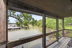 Eine überdachte Terrasse mit Blick auf einen See, angestaute Boote und einen bewaldeten Bereich.