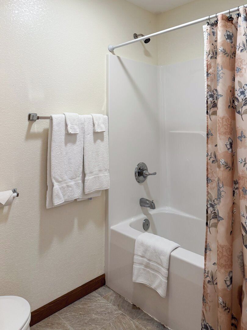 Ein Badezimmer mit Dusche, Badewanne und zwei Handtüchern an einem Handtuchhalter.
