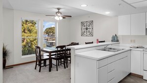A modern kitchen with a central island, white cabinetry, and a view of a body of water through large windows.