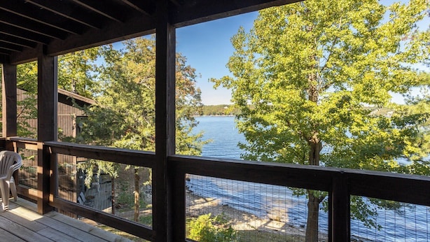 A wooden deck with a view of a lake and trees.