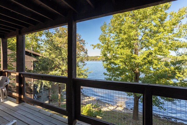 A wooden deck with a view of a lake and trees.