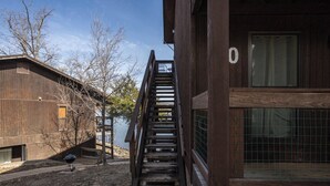 Una escalera de madera que lleva a un edificio con un amplio ventanal y el número '0' en la pared.