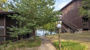 Un sendero lleva a un edificio con un letrero con el número '12', una cerca de madera y un farol.