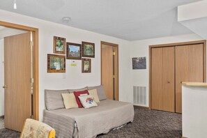 Una habitación con cama, aire acondicionado de pared y puertas de madera.