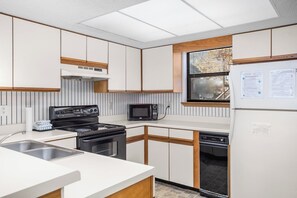 A compact kitchen with a stove, microwave, sink, and refrigerator. - Lone Oak Point 14 - Two Bedroom Apartment, Sleeps 6 (Sunrise Beach)