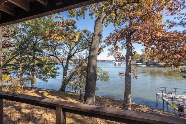 A lakeside view with trees, a dock, and a clear sky.