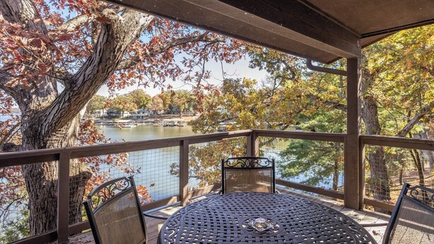 A covered outdoor seating area with a view of a lake and autumn foliage.