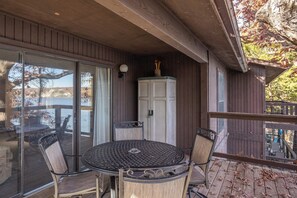 A covered patio with a round table and four chairs, a white cabinet, and a view of a body of water.
