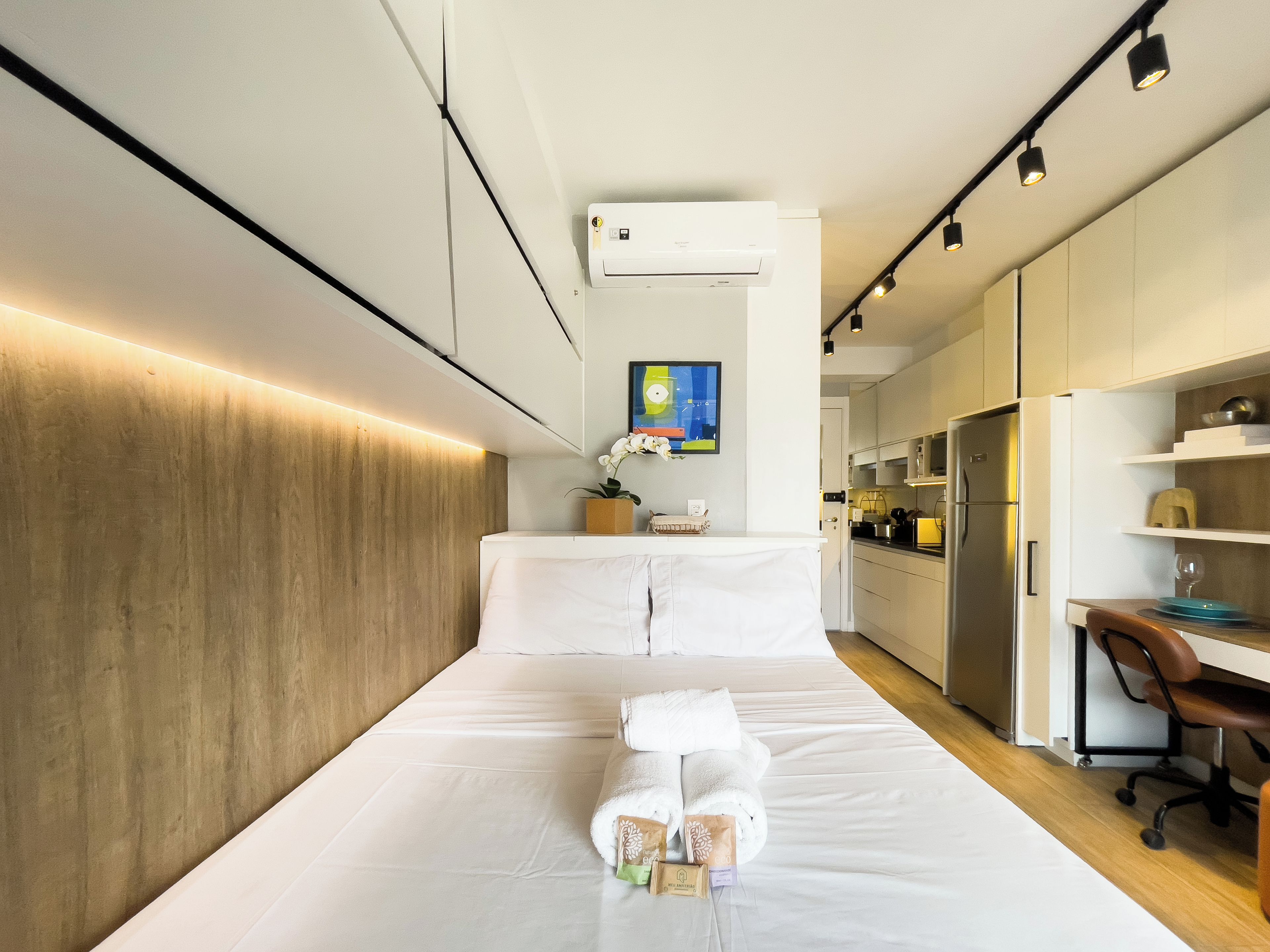 Una camera d'albergo moderna con un letto, una scrivania e angolo cottura.