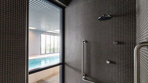 A modern bathroom with a shower, tiled walls, and a window overlooking a pool. - Studio Facto - São Paulo (São Paulo)